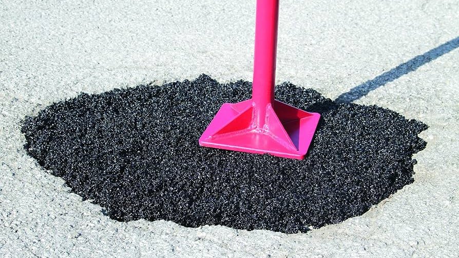A pothole filled with fresh asphalt patch being tamped down